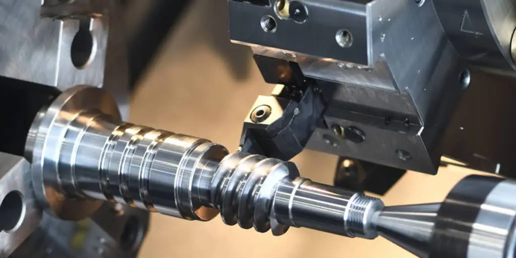 Close-up of a CNC lathe cutting a metal helical gear.