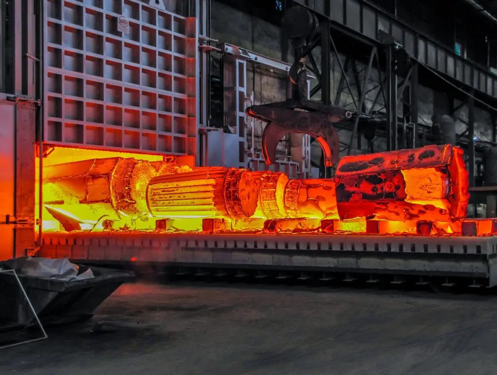 Glowing hot metal billets in an industrial forging process.
