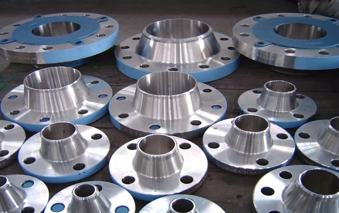 Shiny metal flanges arranged on a surface, showcasing precision engineering.