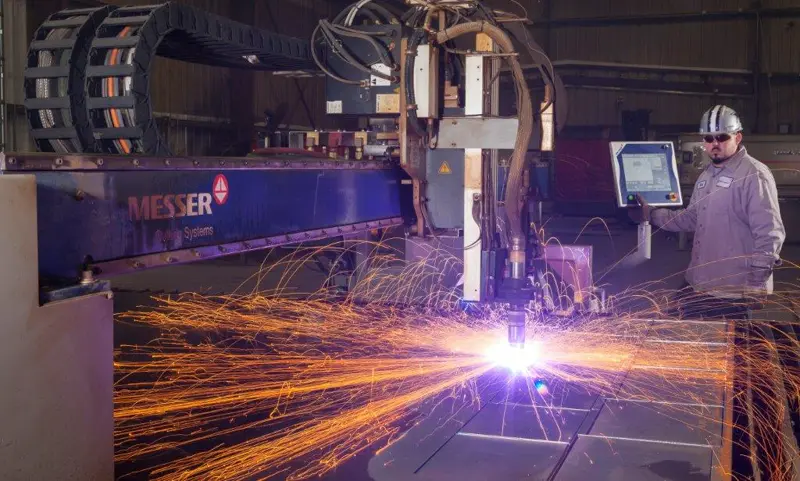 Industrial plasma cutter emitting bright sparks while cutting metal.