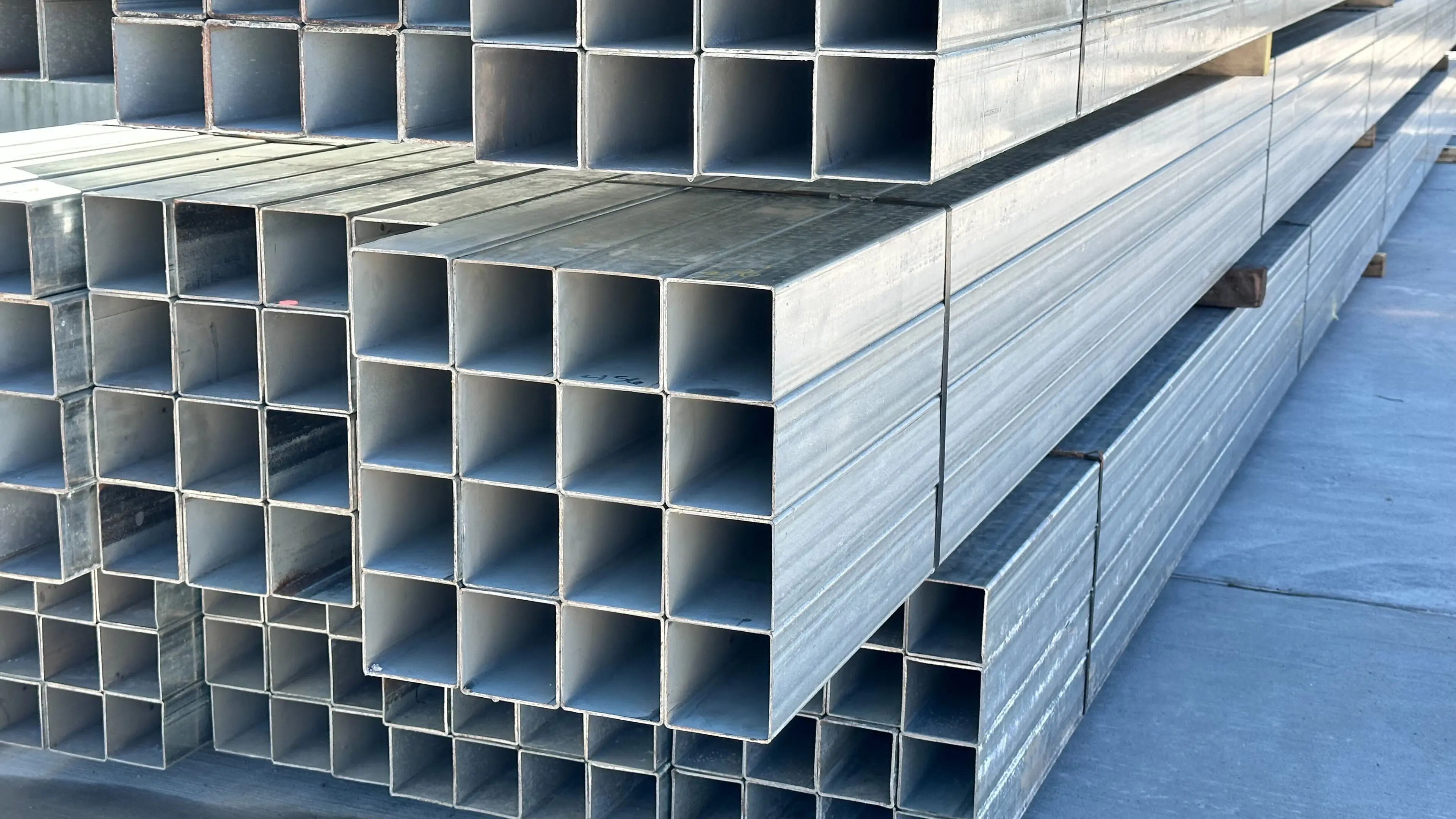 Stacked metal square tubes in a warehouse.